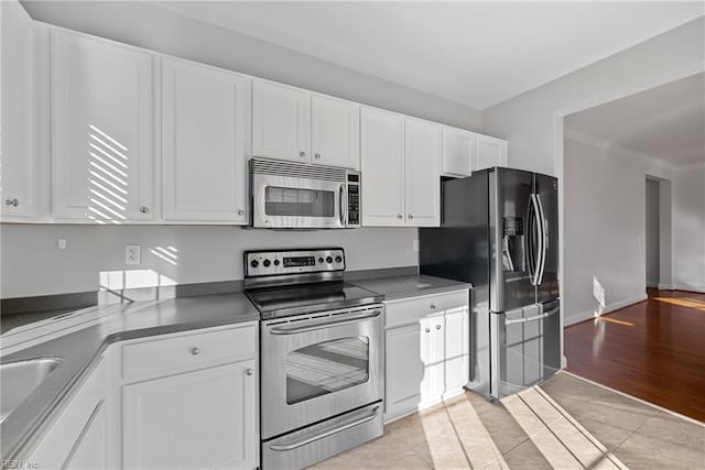 kitchen featuring white cabinetry, crown molding, stainless steel appliances, and light tile patterned flooring