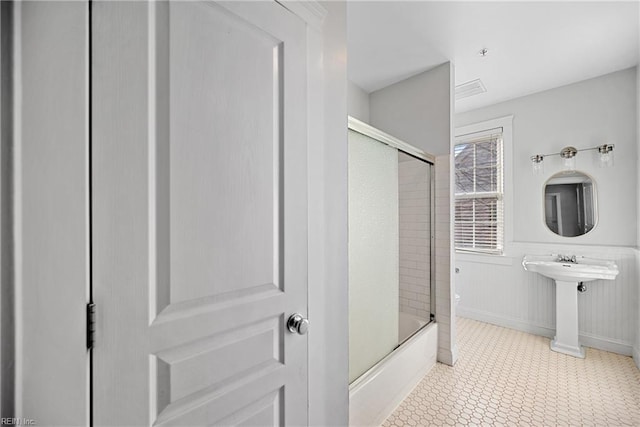 full bathroom featuring toilet, bath / shower combo with glass door, and sink