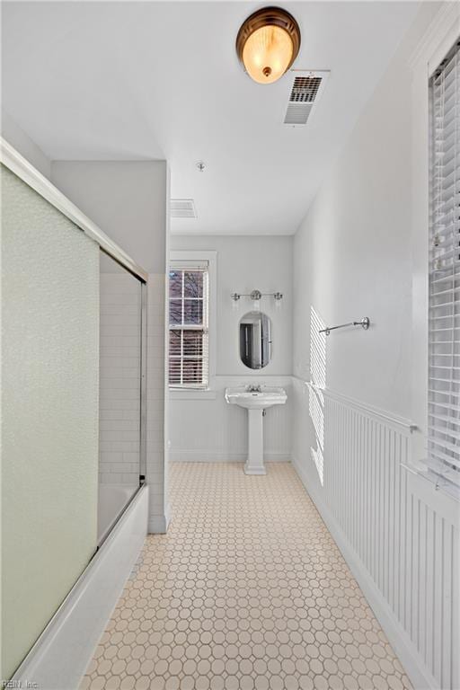 bathroom with sink and bath / shower combo with glass door