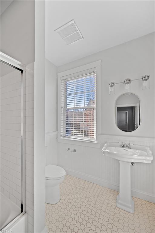 bathroom with enclosed tub / shower combo and toilet