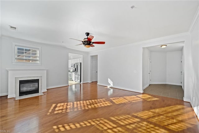 unfurnished living room with ornamental molding, wood-type flooring, and ceiling fan