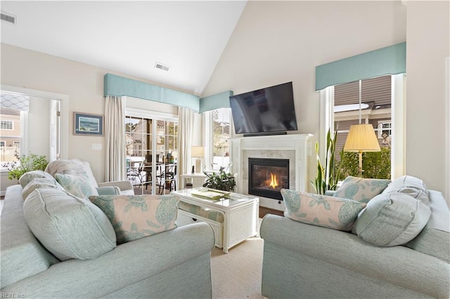 living room featuring a premium fireplace and high vaulted ceiling