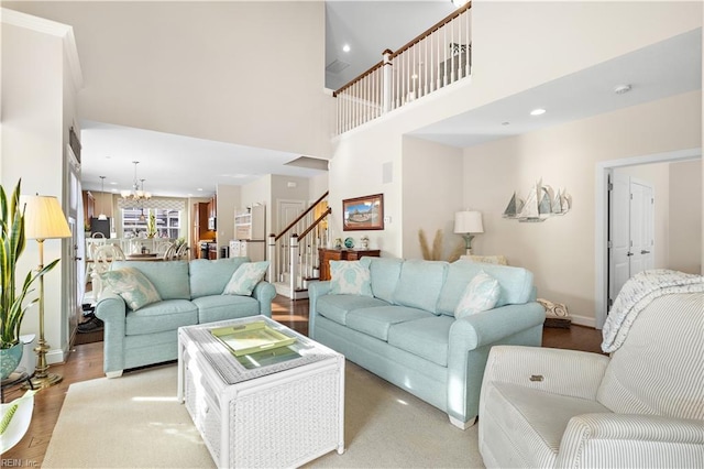 living room featuring a towering ceiling, light hardwood / wood-style flooring, and a notable chandelier