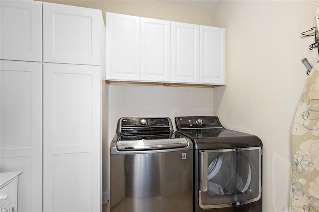 clothes washing area featuring cabinets and independent washer and dryer