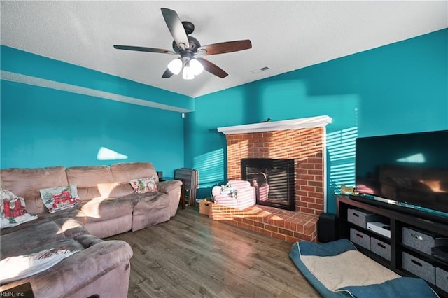 living room featuring ceiling fan, a fireplace, and wood-type flooring