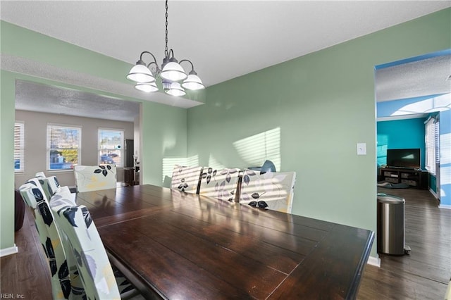 dining area with dark hardwood / wood-style floors, a textured ceiling, and an inviting chandelier