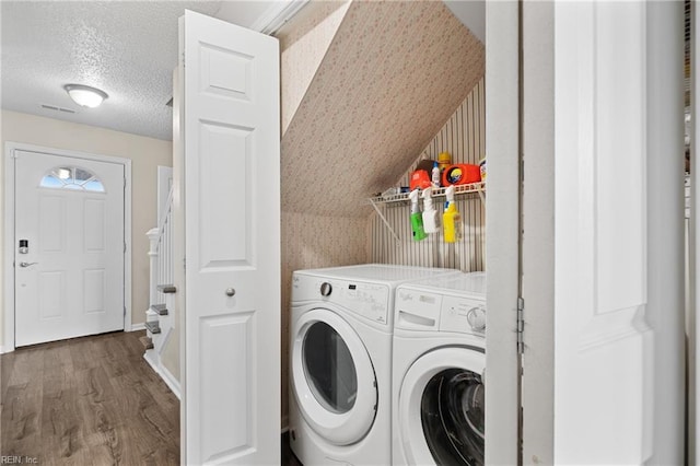 laundry room featuring hardwood / wood-style flooring, a textured ceiling, and washer and clothes dryer