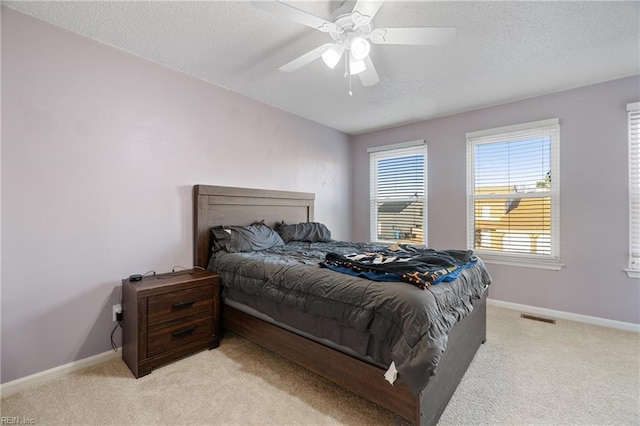 carpeted bedroom with ceiling fan and a textured ceiling