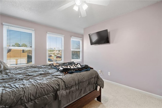 bedroom with ceiling fan, carpet flooring, and a textured ceiling