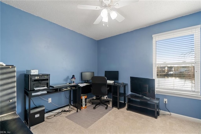 carpeted office space featuring ceiling fan, a healthy amount of sunlight, and a textured ceiling