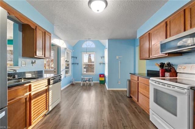 kitchen with sink, appliances with stainless steel finishes, dark hardwood / wood-style floors, a textured ceiling, and decorative light fixtures