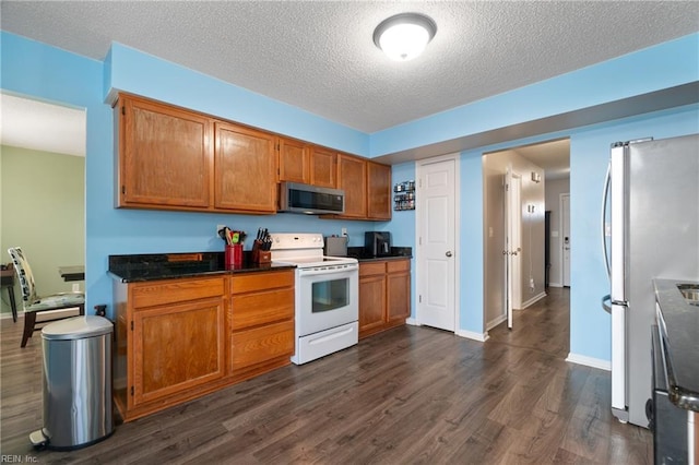 kitchen with appliances with stainless steel finishes, dark wood-type flooring, and a textured ceiling