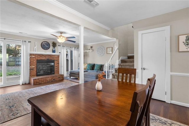 dining room featuring crown molding, ceiling fan, wood-type flooring, and a brick fireplace