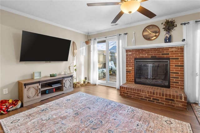 living room with crown molding, a fireplace, dark hardwood / wood-style flooring, and ceiling fan