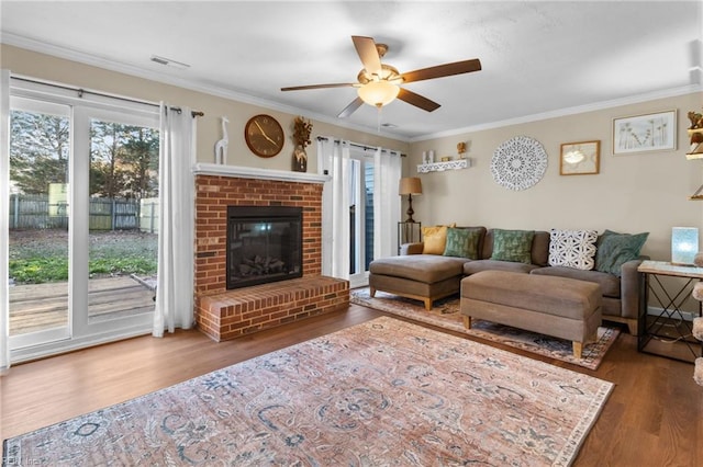 living room featuring crown molding, ceiling fan, dark hardwood / wood-style floors, and a brick fireplace