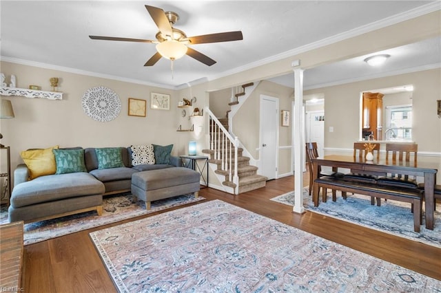 living room with crown molding, dark hardwood / wood-style floors, ceiling fan, and ornate columns