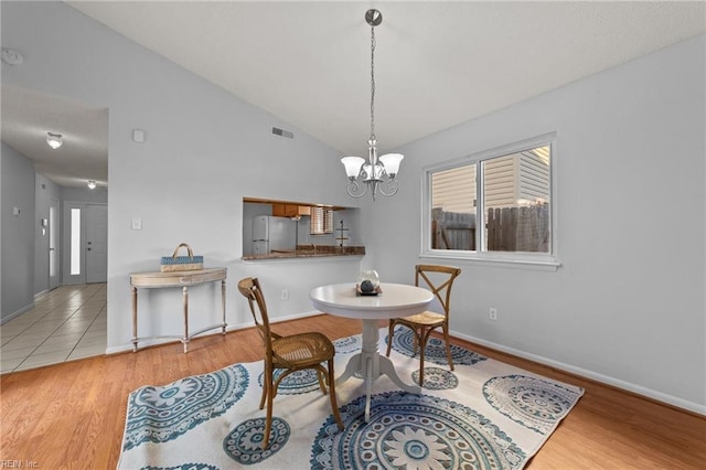 dining space featuring lofted ceiling, a chandelier, and light hardwood / wood-style floors