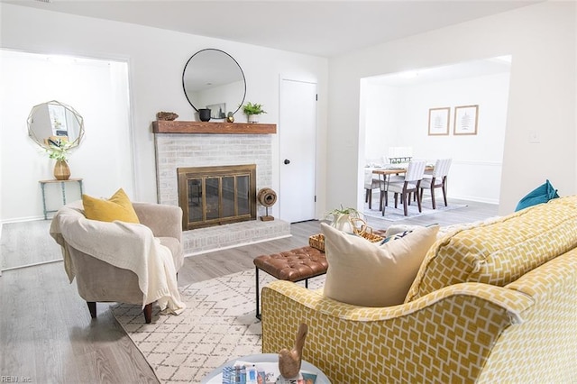 living room with a brick fireplace and hardwood / wood-style flooring