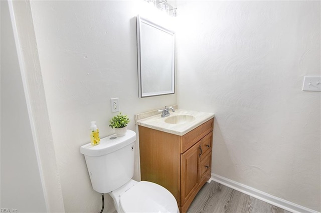 bathroom featuring vanity, wood-type flooring, and toilet