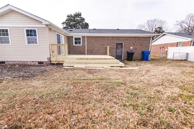 back of house with a wooden deck and a lawn