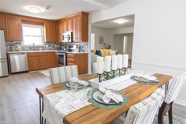 kitchen featuring stainless steel appliances, sink, light hardwood / wood-style floors, and decorative backsplash