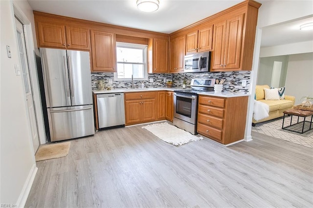 kitchen featuring appliances with stainless steel finishes, sink, light hardwood / wood-style flooring, and decorative backsplash