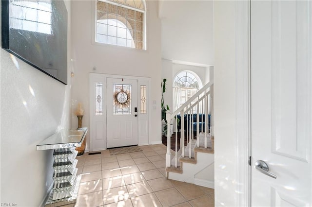 entryway with light tile patterned floors and a high ceiling