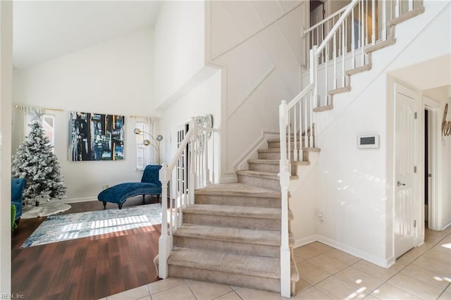 stairs with tile patterned flooring and high vaulted ceiling