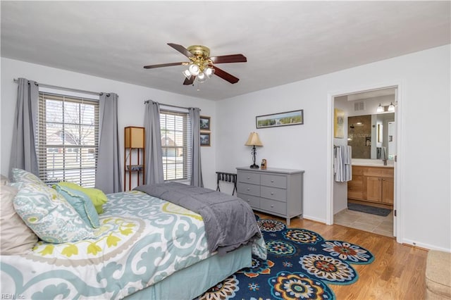 bedroom with ceiling fan, ensuite bathroom, and light hardwood / wood-style floors