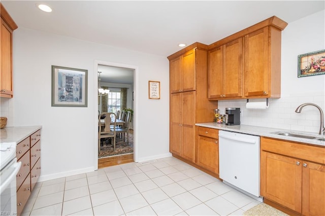 kitchen with sink, range, white dishwasher, tasteful backsplash, and light stone countertops