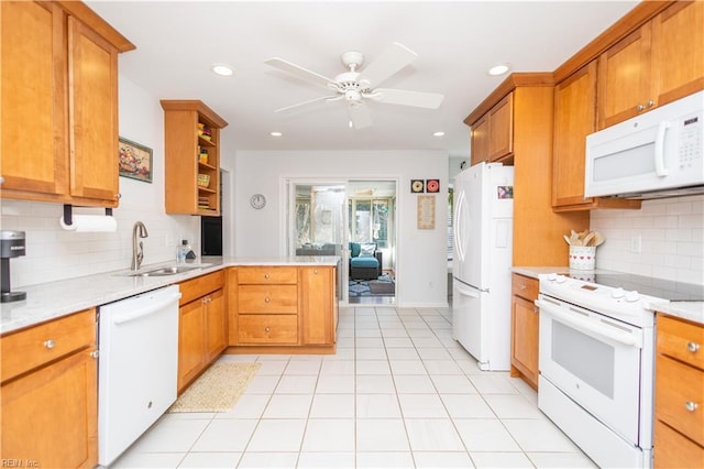 kitchen with light stone countertops, sink, white appliances, and kitchen peninsula