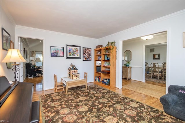 living area with hardwood / wood-style floors and crown molding