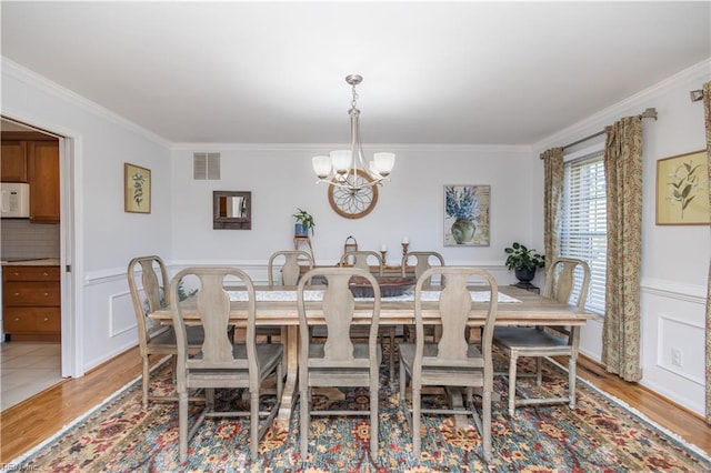 dining area with ornamental molding and light hardwood / wood-style flooring