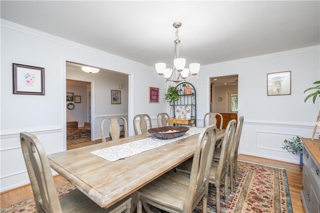 dining area with crown molding, light hardwood / wood-style flooring, and a chandelier