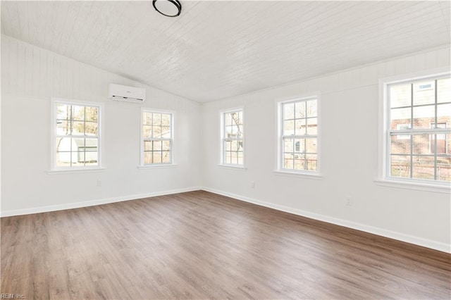 unfurnished room with hardwood / wood-style flooring, lofted ceiling, and a wall mounted air conditioner