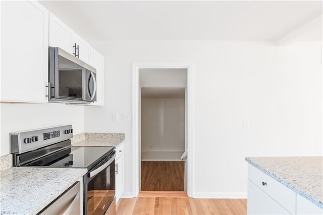 kitchen featuring light hardwood / wood-style flooring, light stone countertops, white cabinets, and appliances with stainless steel finishes