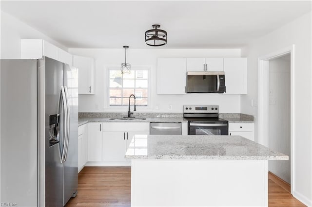 kitchen with appliances with stainless steel finishes, sink, a kitchen island, and white cabinets