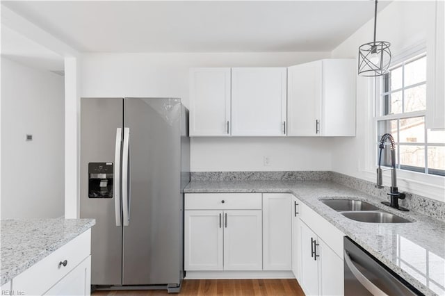 kitchen featuring pendant lighting, sink, white cabinets, stainless steel appliances, and light stone countertops