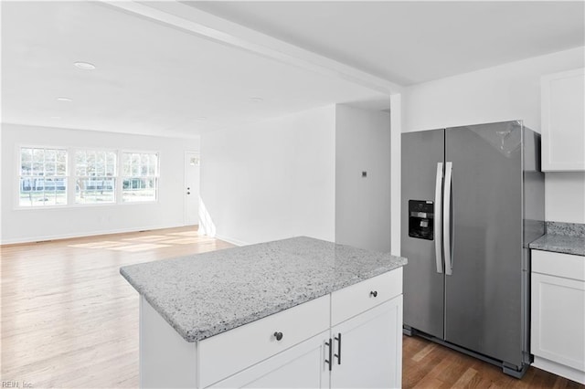 kitchen with white cabinetry, light stone counters, wood-type flooring, a center island, and stainless steel fridge with ice dispenser