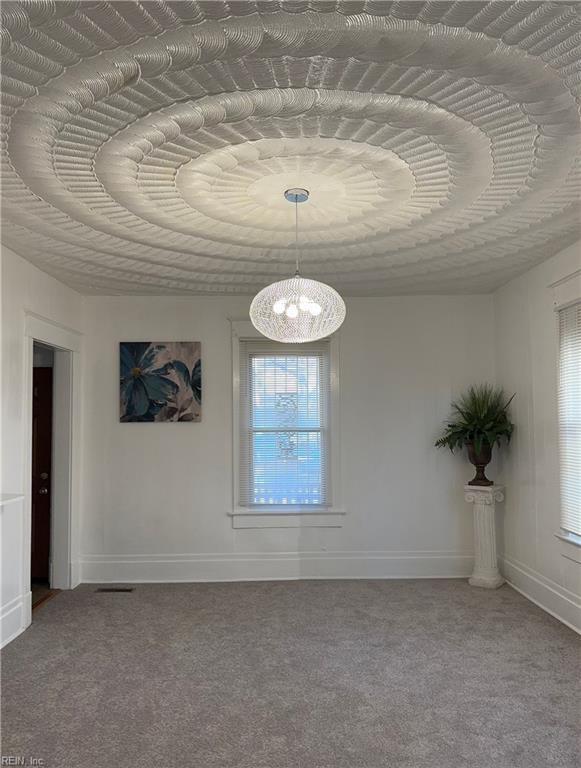 unfurnished room featuring carpet flooring and a notable chandelier