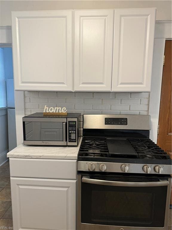 kitchen with white cabinetry, appliances with stainless steel finishes, and dark tile patterned floors