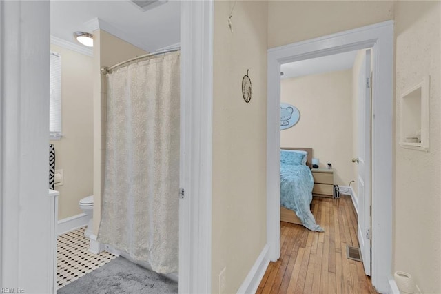 bathroom with hardwood / wood-style floors, crown molding, and toilet