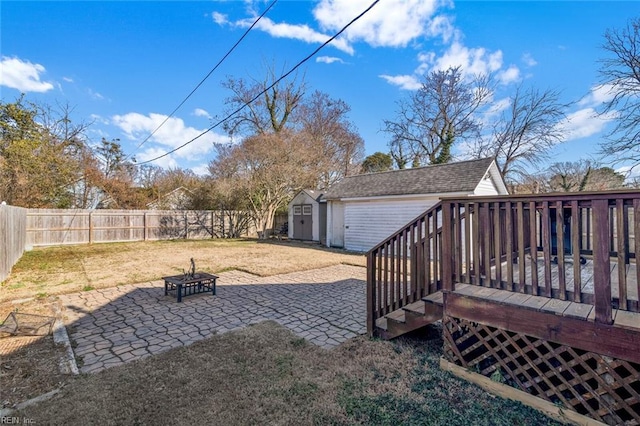 view of yard with a patio, a deck, a shed, and a fire pit