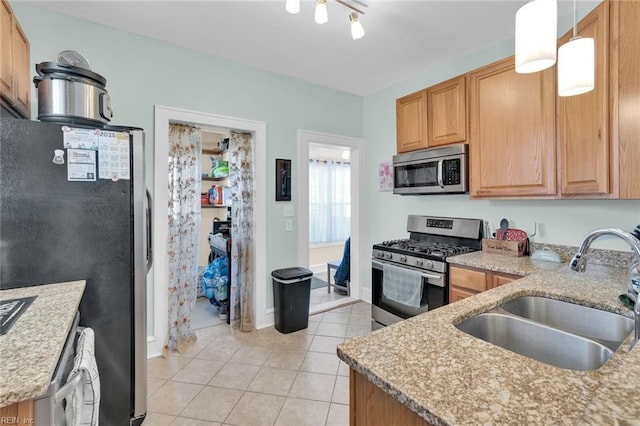 kitchen with sink, light tile patterned floors, stainless steel appliances, light stone counters, and decorative light fixtures