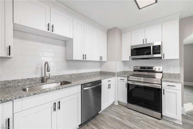 kitchen with sink, stainless steel appliances, white cabinets, and light wood-type flooring