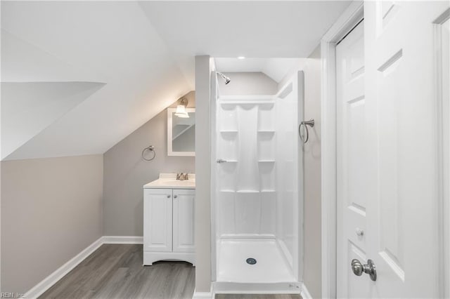 bathroom with walk in shower, vanity, vaulted ceiling, and hardwood / wood-style flooring