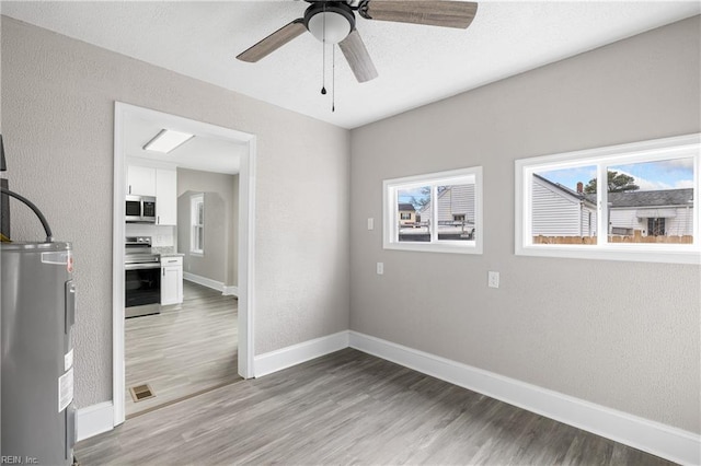 unfurnished room featuring hardwood / wood-style flooring, electric water heater, and ceiling fan