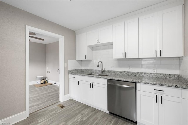 kitchen featuring light stone counters, sink, stainless steel dishwasher, and white cabinets