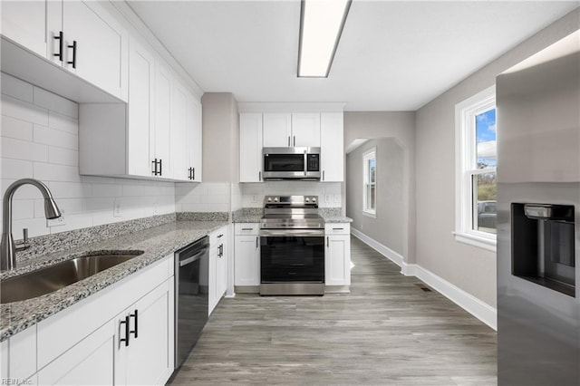 kitchen with light stone counters, sink, white cabinets, and appliances with stainless steel finishes