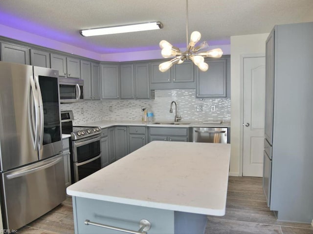 kitchen with sink, gray cabinetry, stainless steel appliances, a center island, and dark hardwood / wood-style flooring